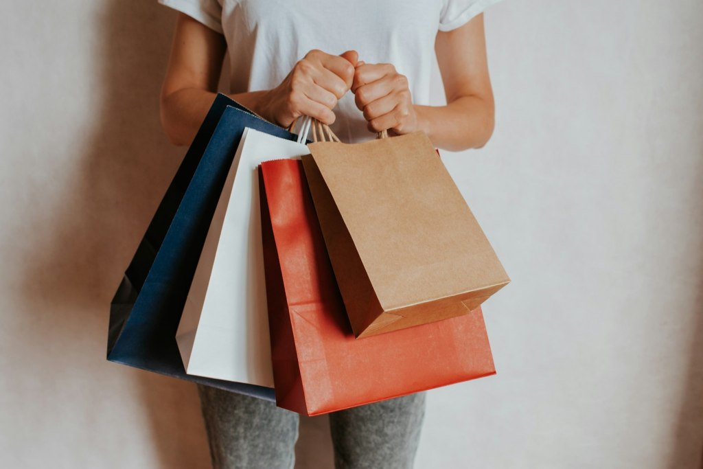 A smiling woman holding a paper shopping bag in a store during a holiday sale