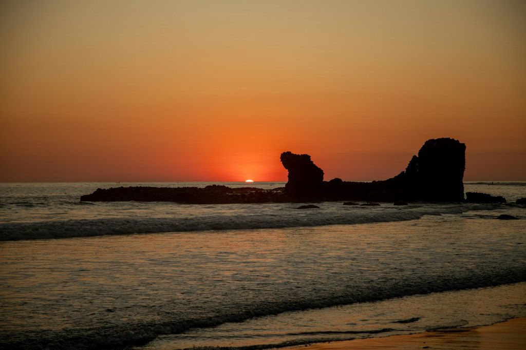 Silhouette of a rock formation in the sea at sunset on El Salvador's Pacific coast near El Tunco