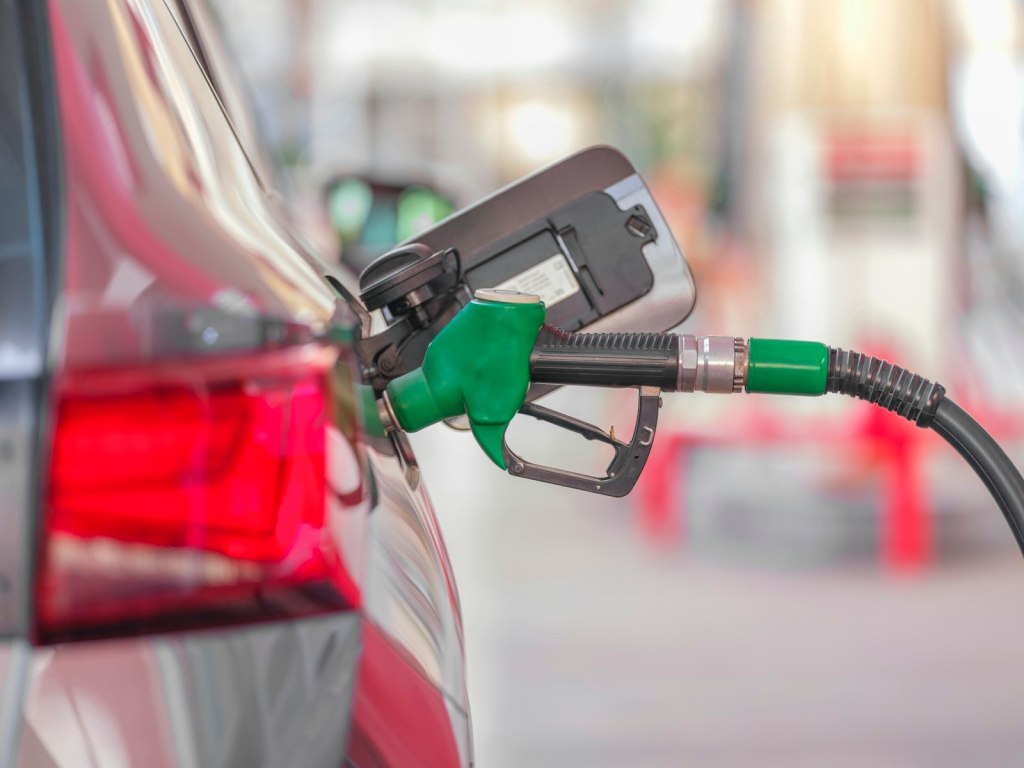 A gas pump nozzle inserted into a car's fuel tank at a gas station