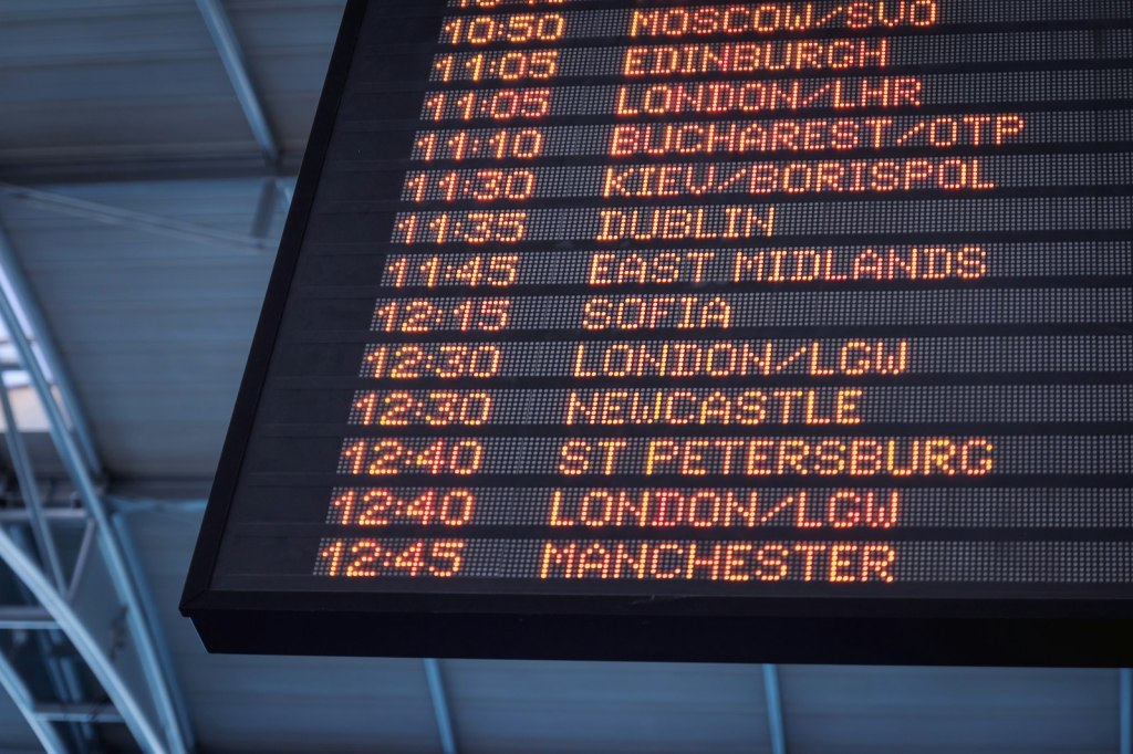 Low-angle view of an airport departure board listing flights