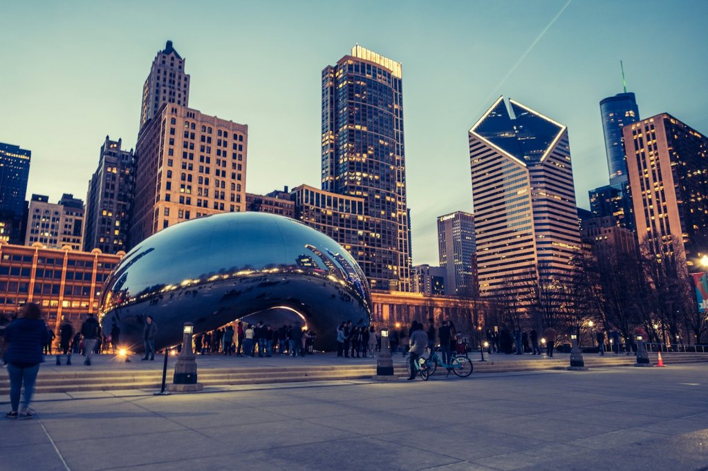 Visitors gathered around a large reflective sculpture in downtown Chicago