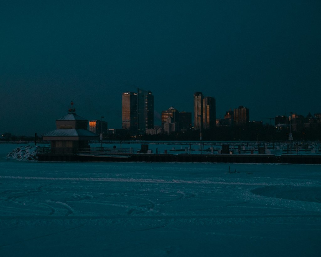 A Milwaukee high-rise lit up at night beside ice-covered water in winter