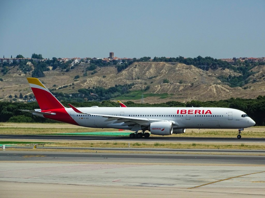 A white and red Iberia airliner at an airport