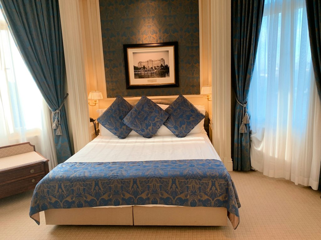 Neatly made hotel bed with white and brown floral linens