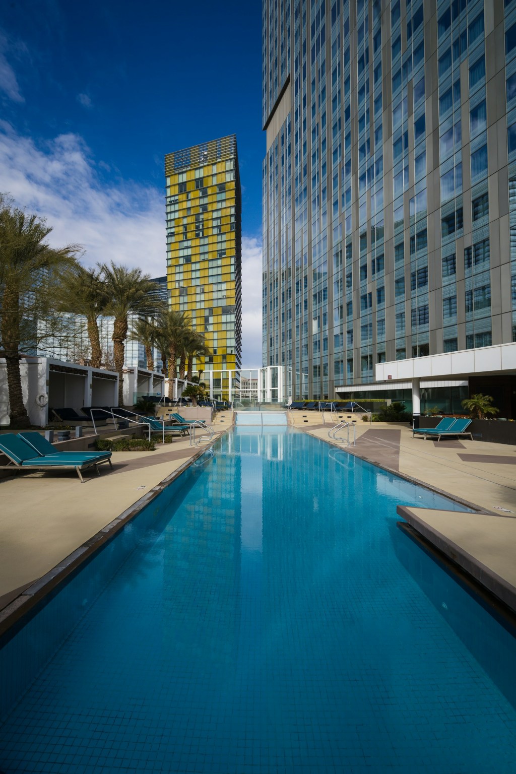 Large hotel swimming pool next to a tall hotel building