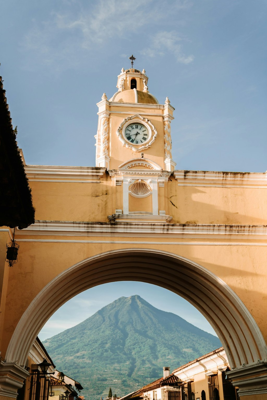A colonial clock tower in Antigua, Guatemala, with a volcano in the background