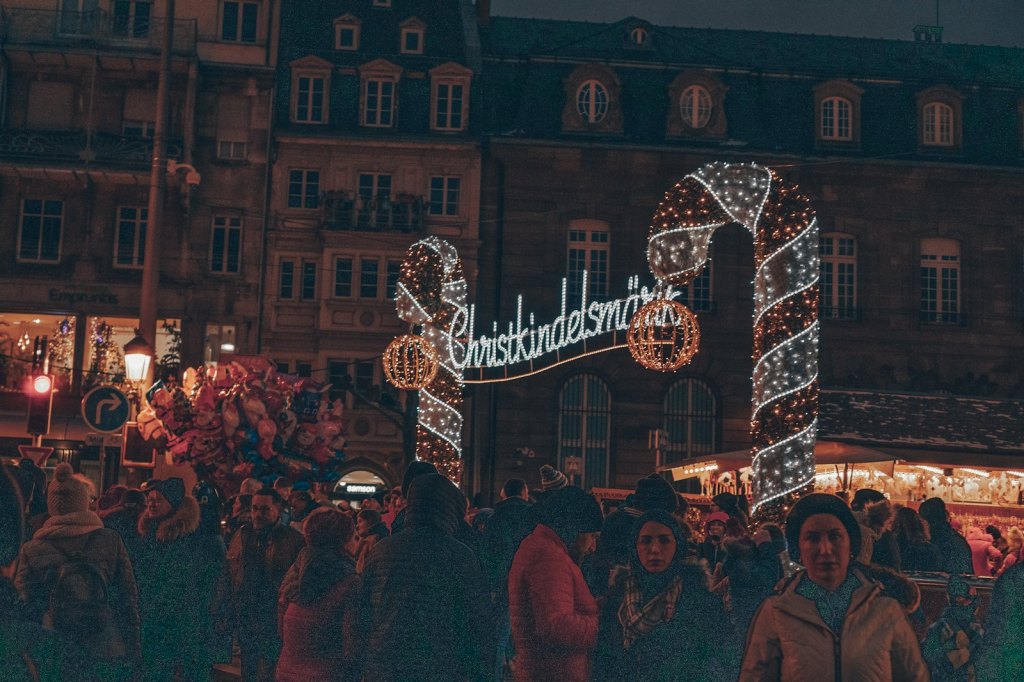 Crowds walking between wooden stalls at a Christmas market