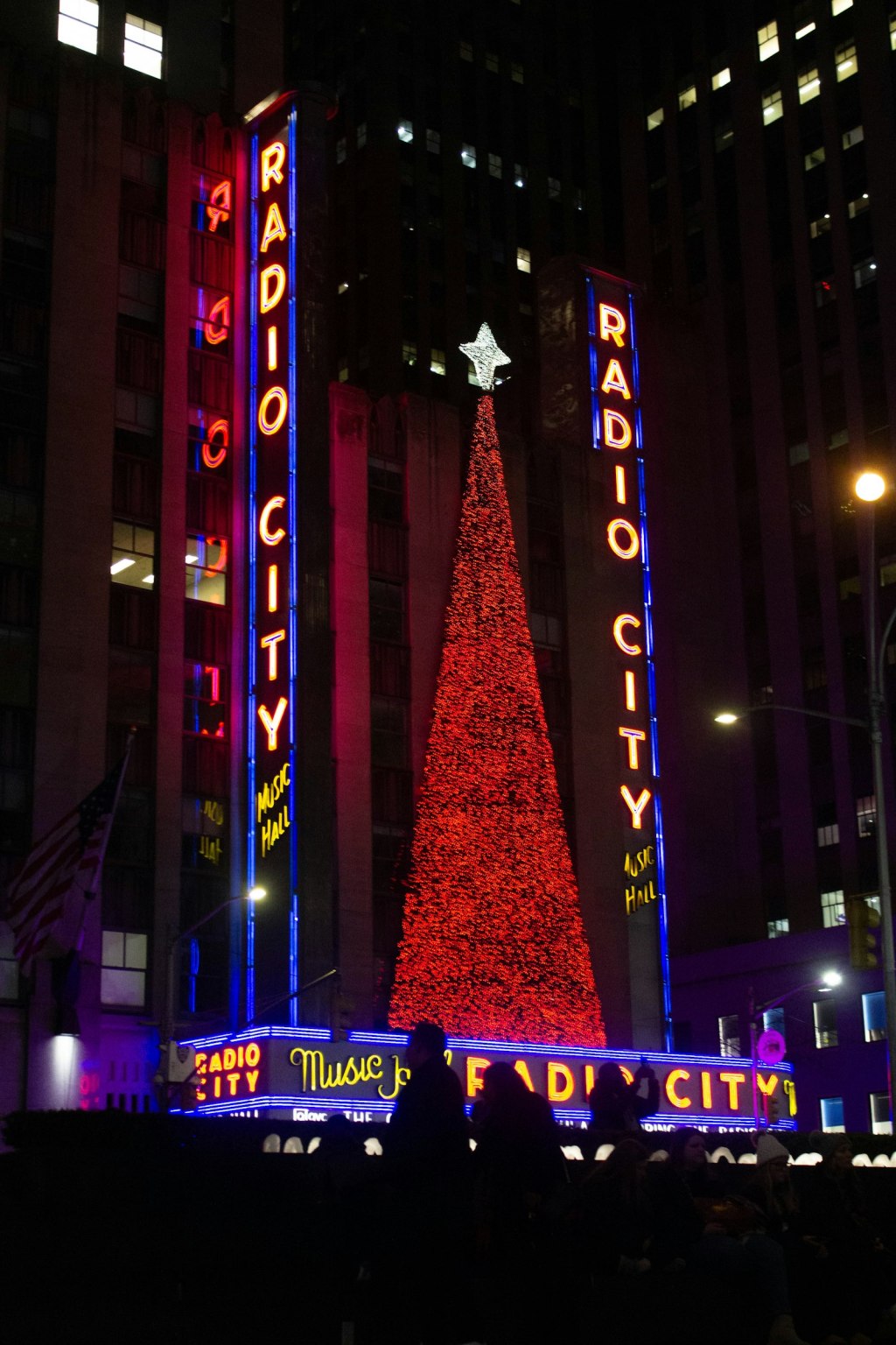 Lit Christmas tree glowing at night on a Manhattan street near Radio City Music Hall in New York City
