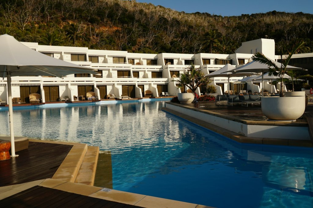 A resort hotel with a large swimming pool surrounded by umbrellas