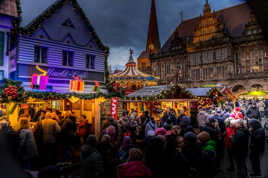 Crowds browsing wooden stalls at a traditional German Christmas market at dusk