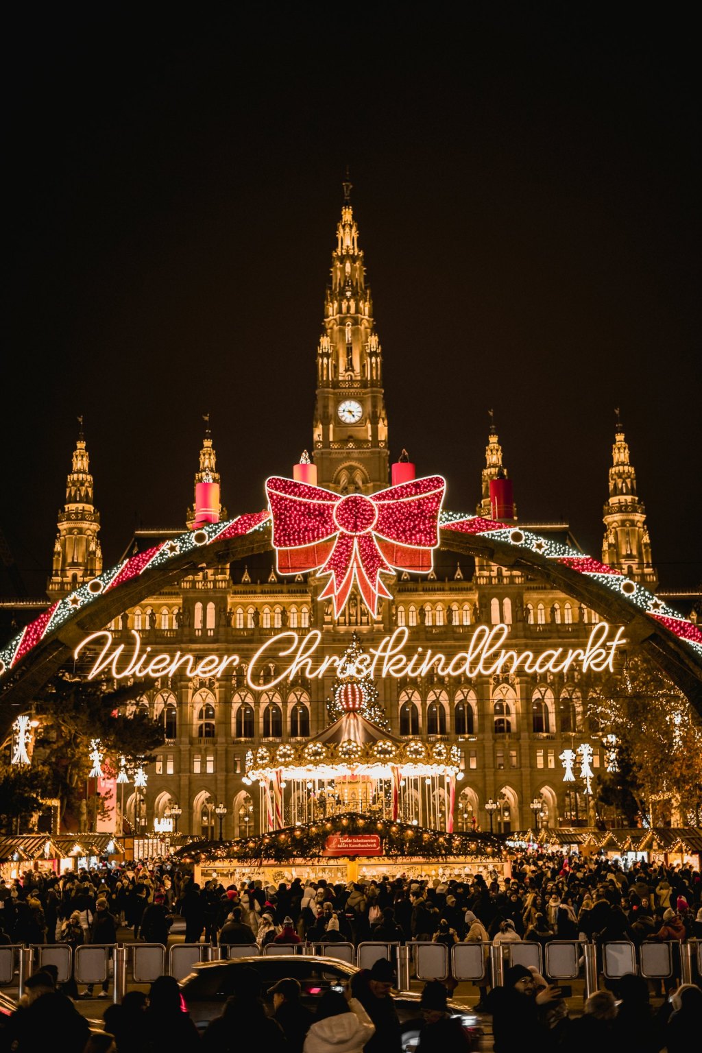 A grand historic building behind a Christmas light display and market stalls
