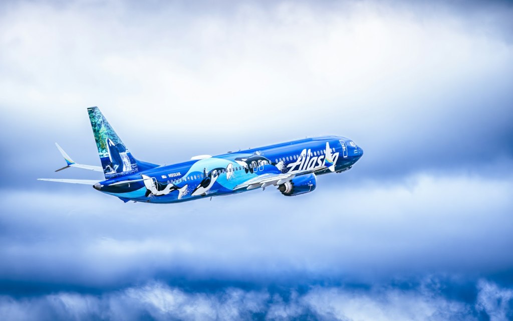 An Alaska Airlines jet flying through a cloudy sky