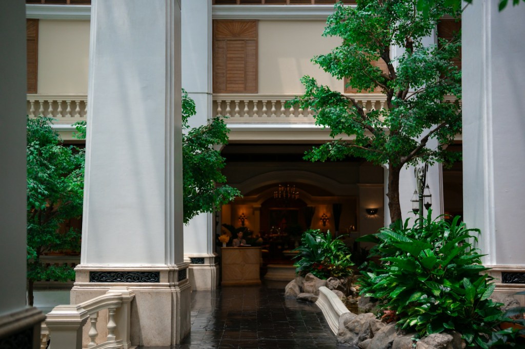 Elegant hotel interior with lush trees and tall columns