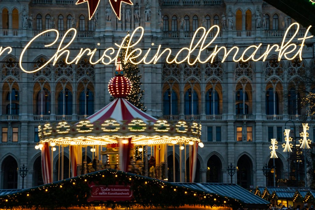 An illuminated carousel at a Christmas market at night
