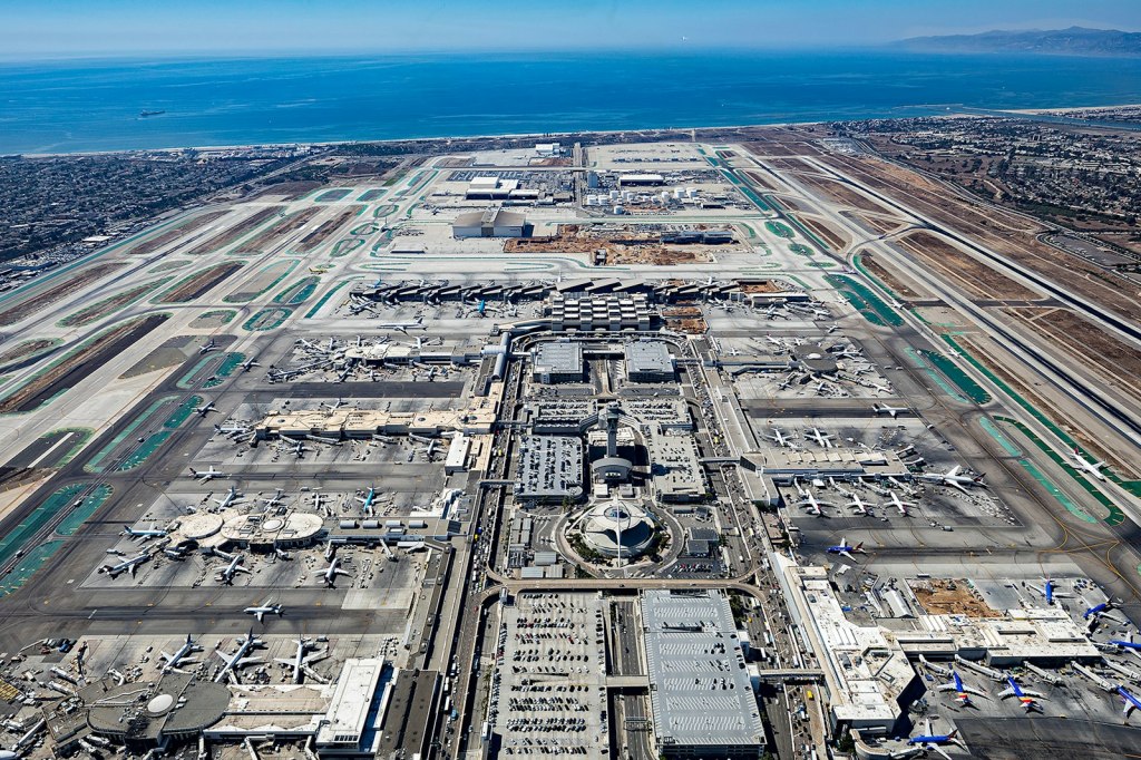 Aerial view of Los Angeles International Airport terminals and runways with the Pacific Ocean behind