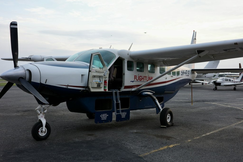 A single-engine Cessna Caravan turboprop parked on the tarmac with its door open