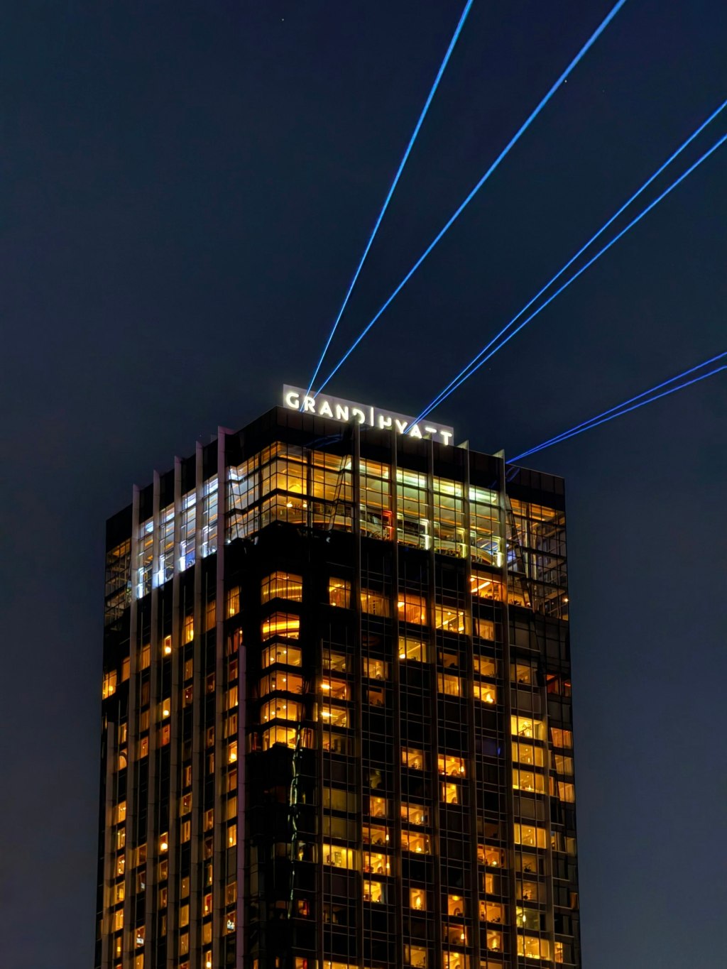 Grand Hyatt hotel tower illuminated at night with laser lights