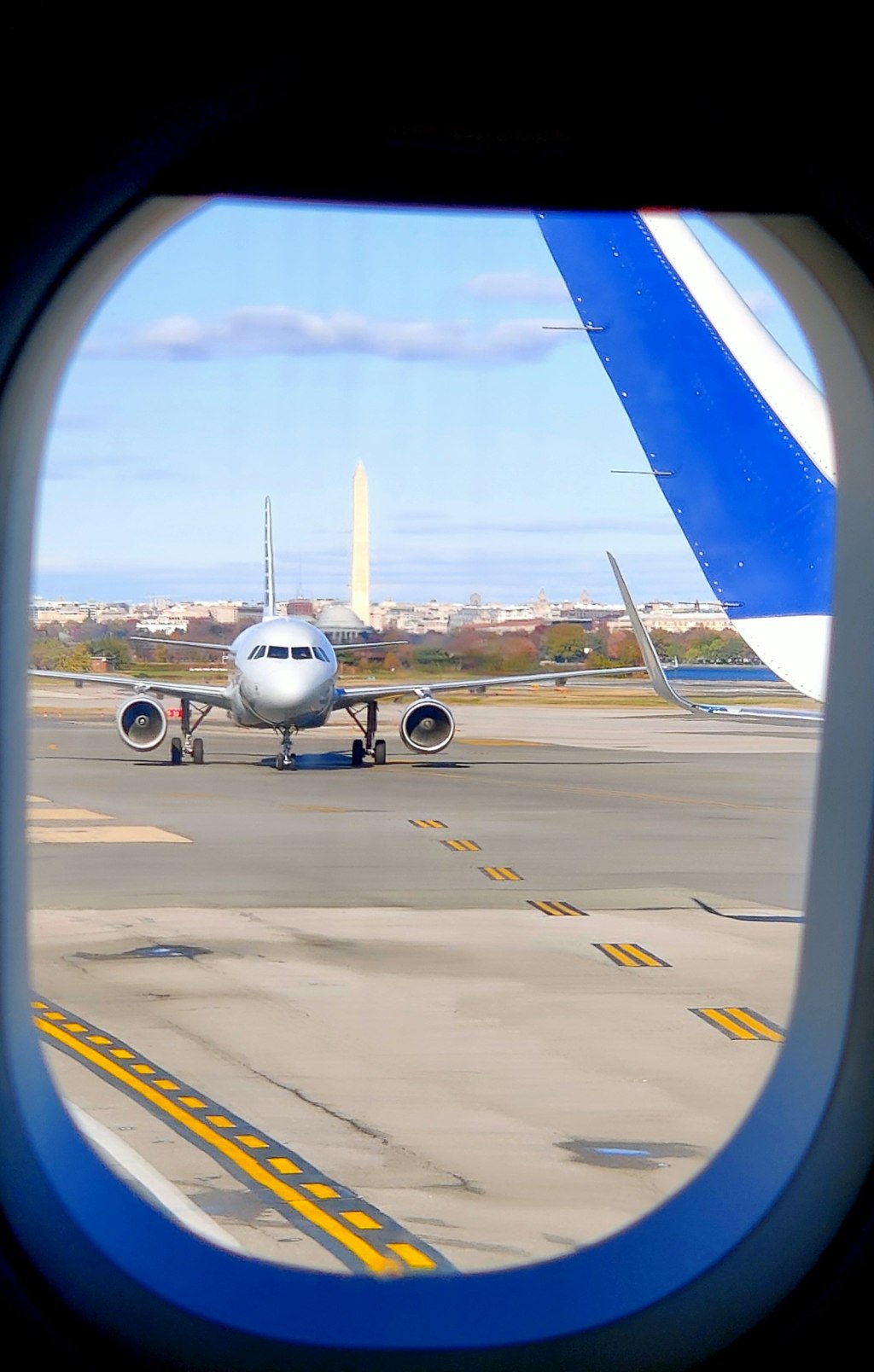 A passenger airplane on an airport tarmac with the Washington Monument visible in the background