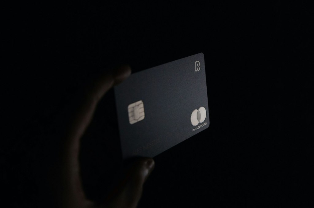 A hand holding a black premium credit card