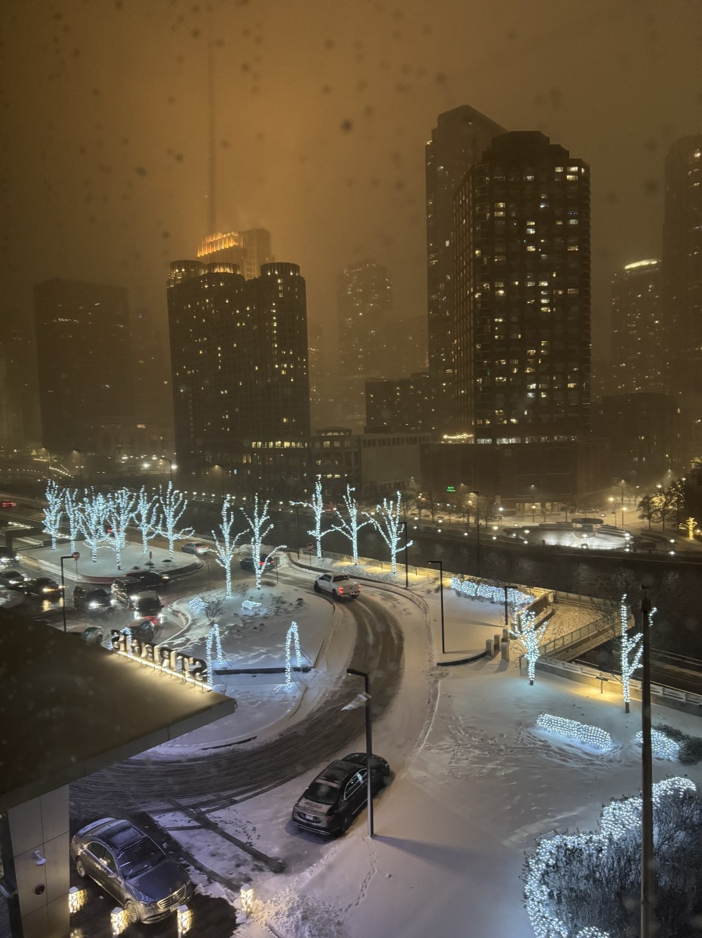Snowy night view of Chicago high-rises and lit trees from a St. Regis Chicago hotel room window